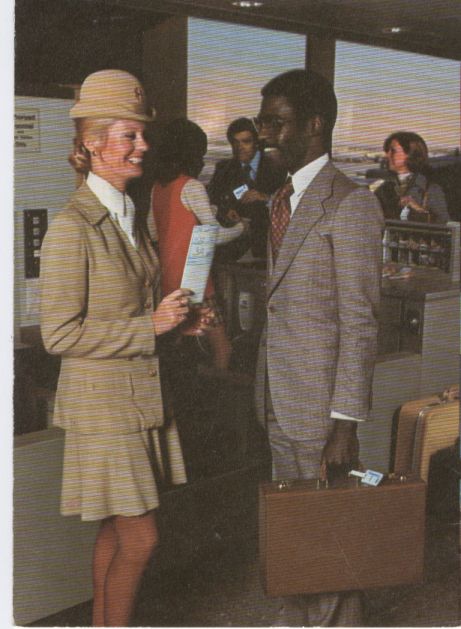 1970s A Flight Attendant in a Galaxy Gold uniform greets a boarding customer at Pan Am's WorldPort at New York, JFK Airport